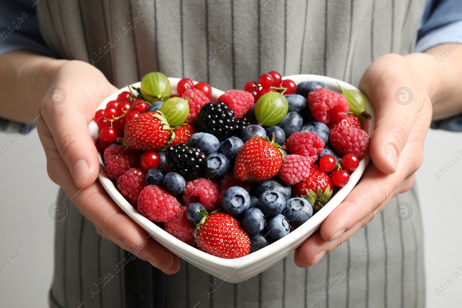 Photo of Woman with bowl of delicious summer berries, closeup