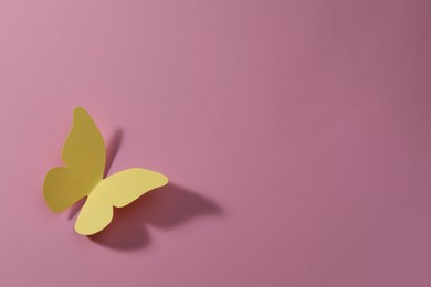 Photo of Yellow paper butterfly on pink background, top view. Space for text