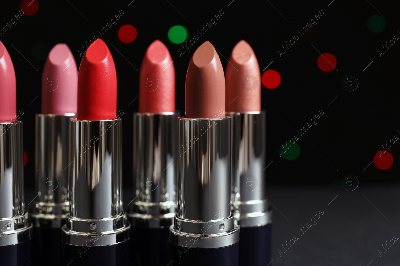 Photo of Different lipsticks against blurred lights. Cosmetic product