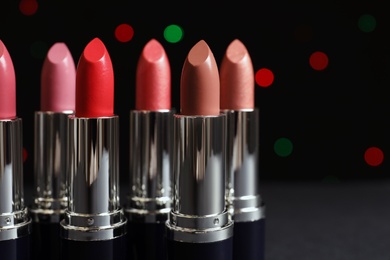 Photo of Different lipsticks against blurred lights. Cosmetic product