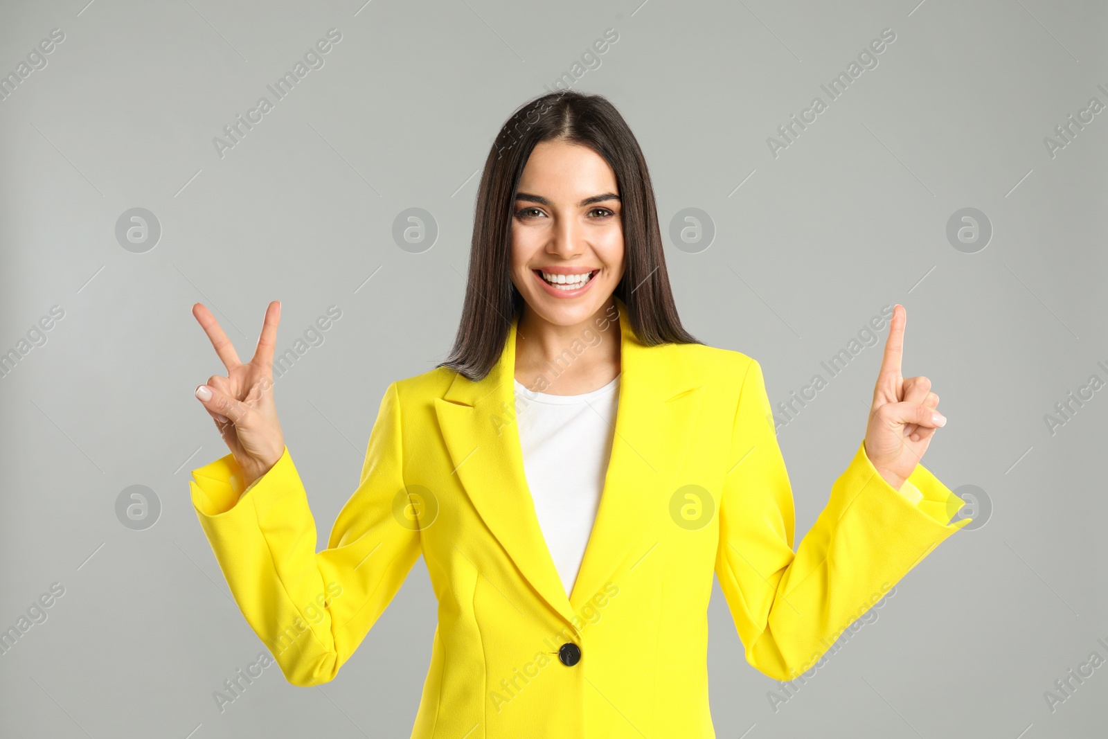 Photo of Woman showing number three with her hands on grey background