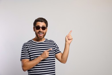 Photo of Portrait of excited bearded man with stylish sunglasses on light grey background. Space for text