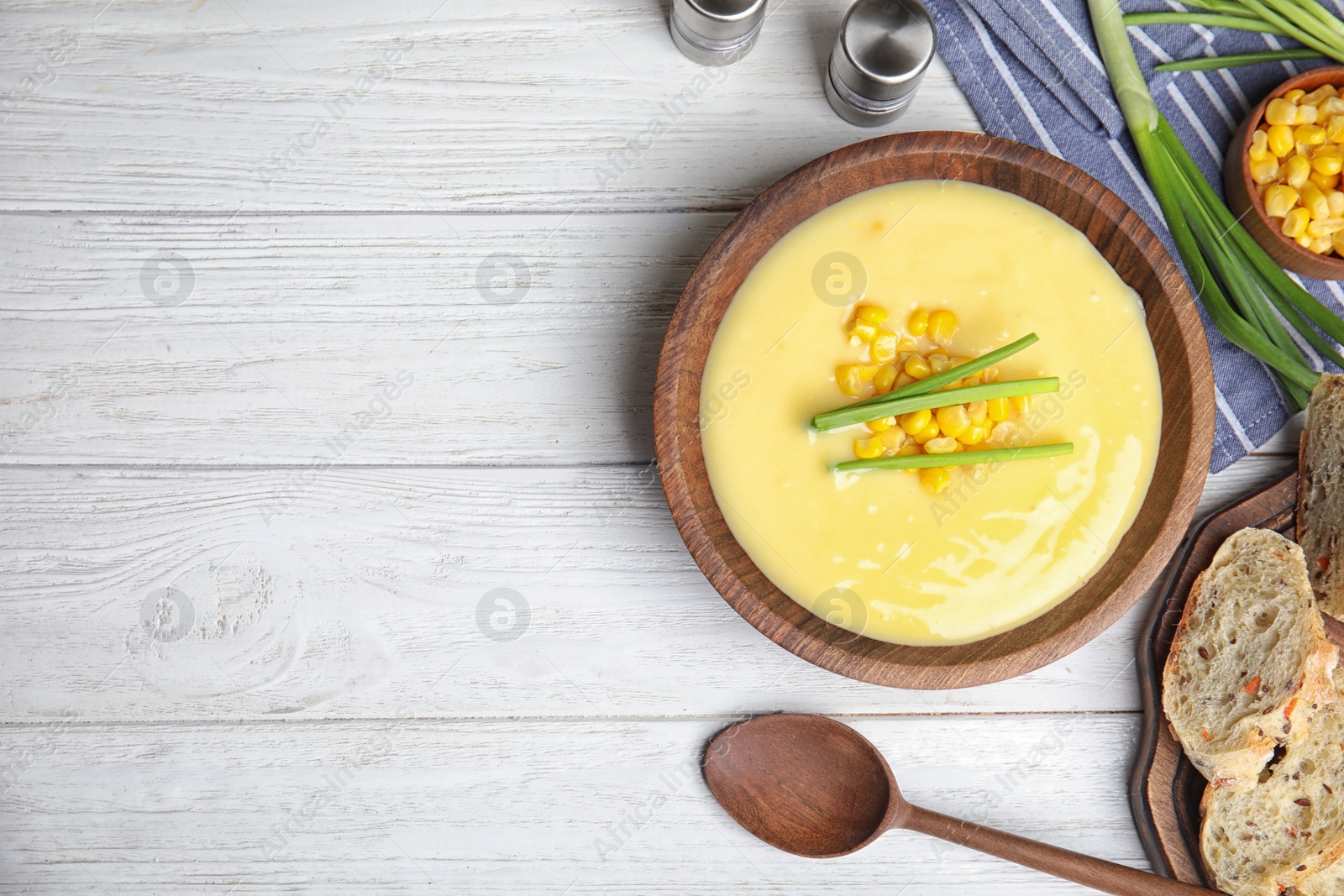 Photo of Delicious corn cream soup served on white wooden table, flat lay. Space for text