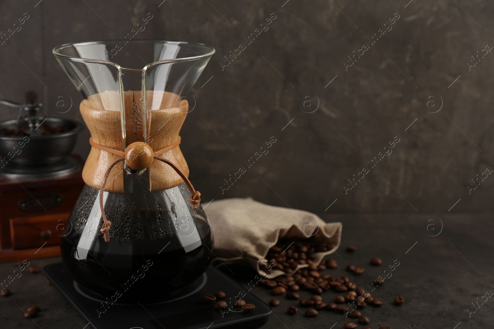 Photo of Making drip coffee. Glass chemex coffeemaker, beans and scales on gray table, space for text