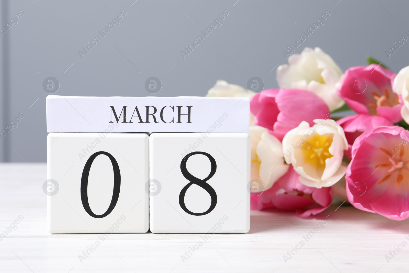 Photo of International Women's day - 8th of March. Wooden block calendar and beautiful flowers on white table