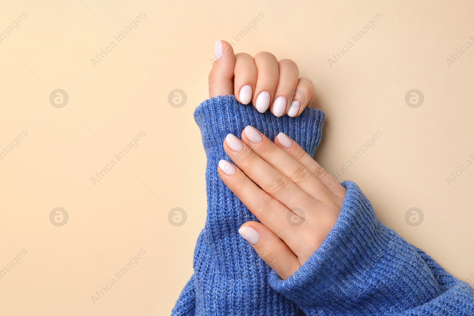 Photo of Woman showing her manicured hands with white nail polish on beige background, top view. Space for text