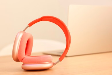 Photo of Modern headphones and laptop on wooden table