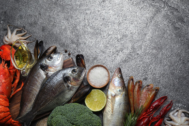 Fresh fish and different seafood on grey table, flat lay. Space for text