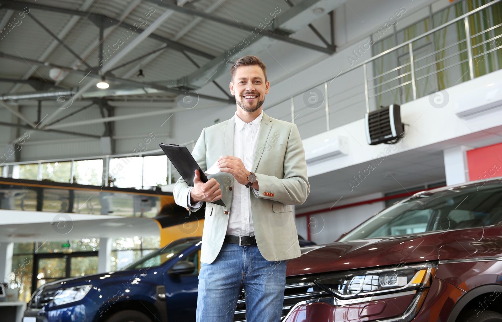 Photo of Salesman with clipboard in modern car dealership