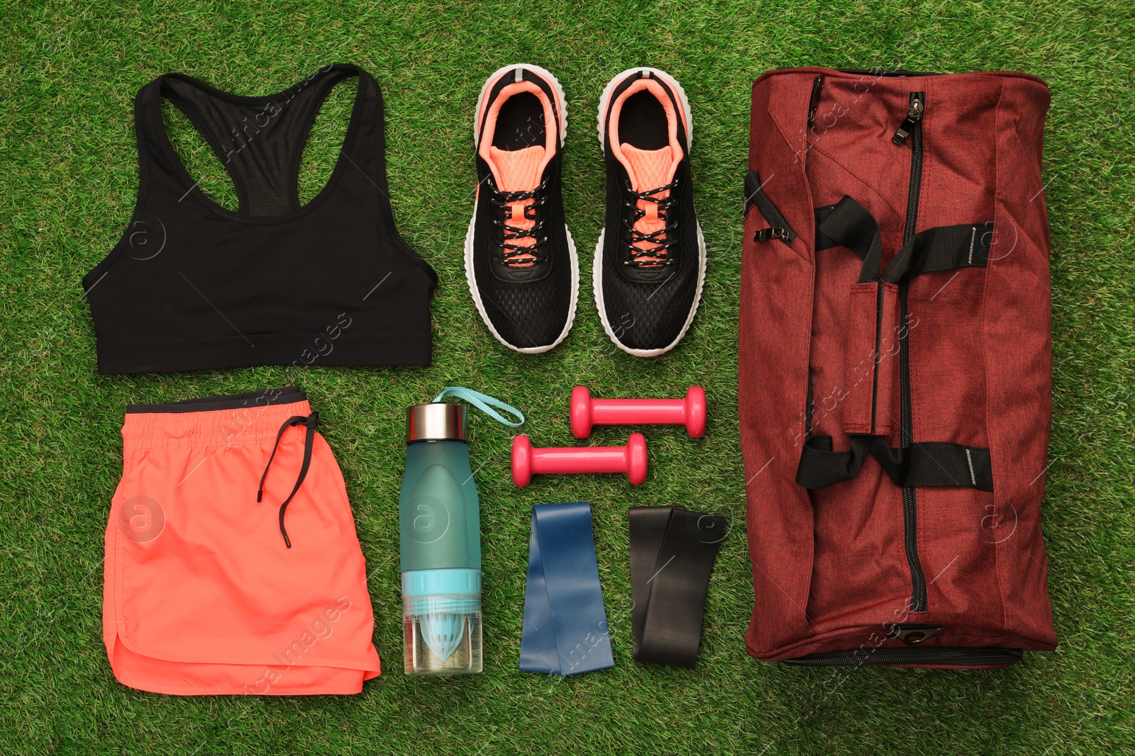 Photo of Gym bag and sports equipment on green grass, flat lay