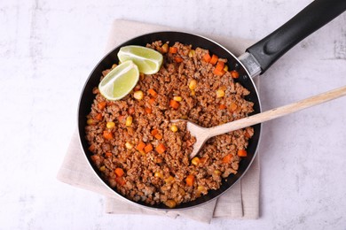 Fried minced meat, carrot, corn and lime in pan on white textured table, top view