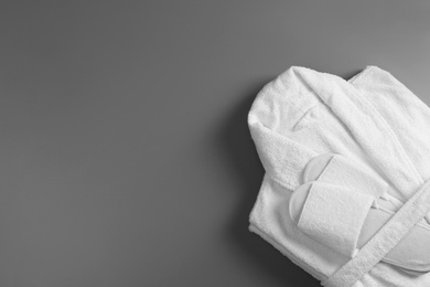 Photo of Clean folded bathrobe and slippers on grey background, top view. Space for text