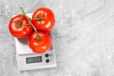 Kitchen scale with tomatoes on grey textured table, top view. Space for text