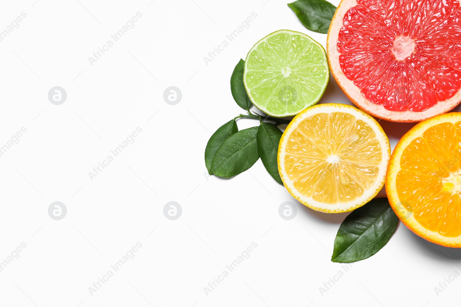 Photo of Different cut citrus fruits and leaves on white table, flat lay. Space for text