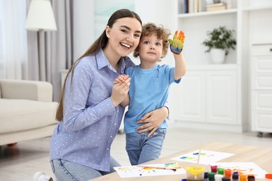 Photo of Mother and her little son painting with palms at home