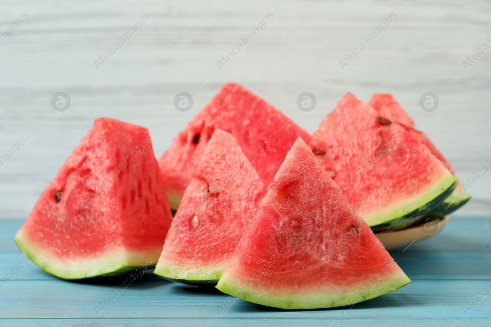 Photo of Slices of tasty ripe watermelon on turquoise wooden table, closeup