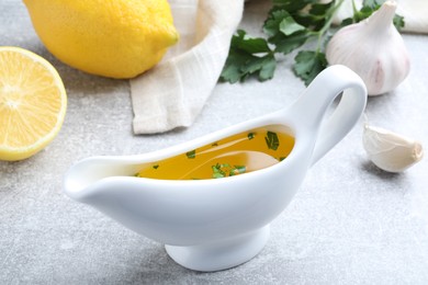 Photo of Ceramic boat with lemon sauce on light table. Delicious salad dressing