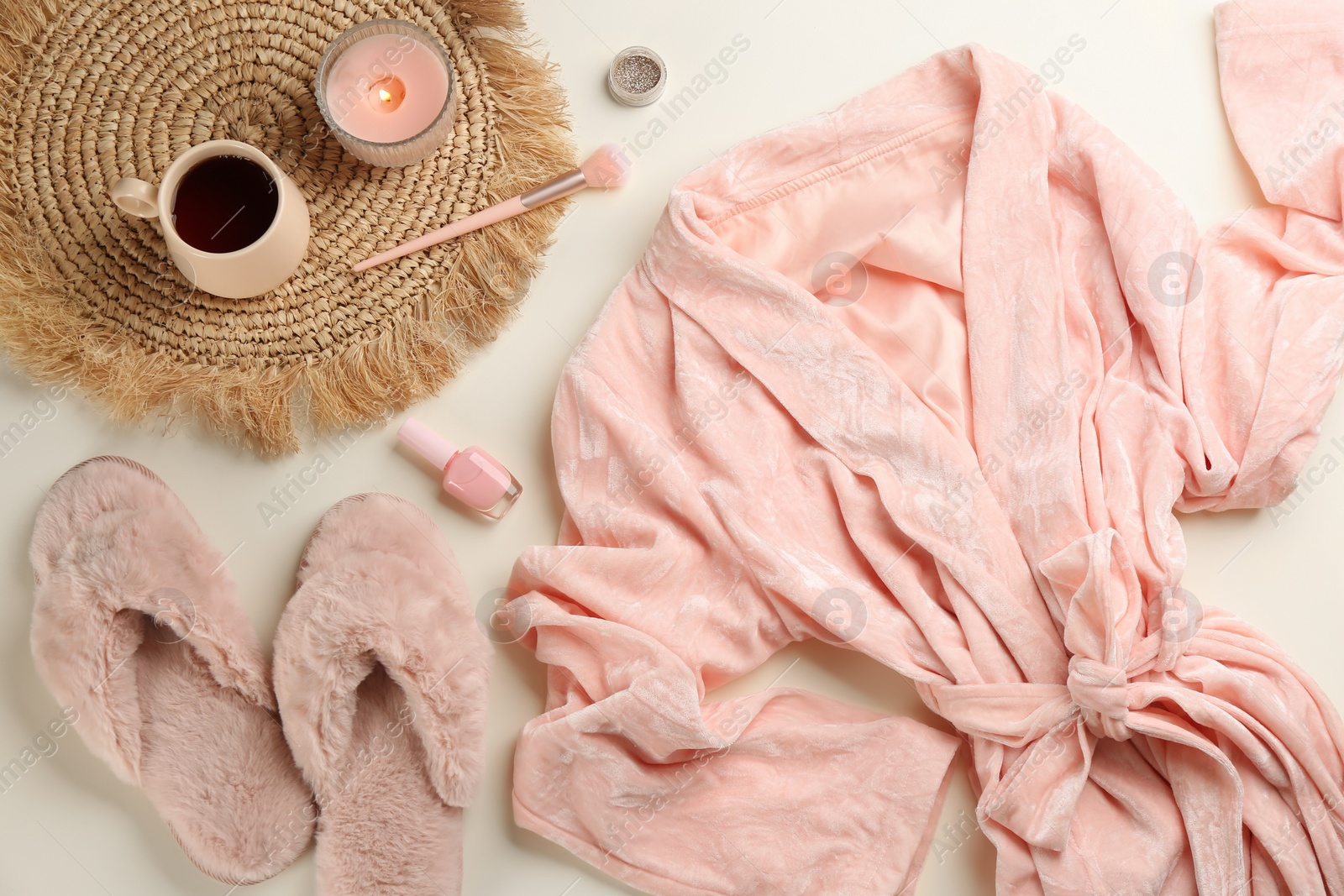 Photo of Flat lay composition with fluffy slippers and robe on beige background. Comfortable home outfit