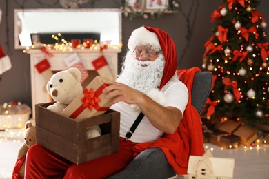 Photo of Authentic Santa Claus holding wooden crate with gifts indoors