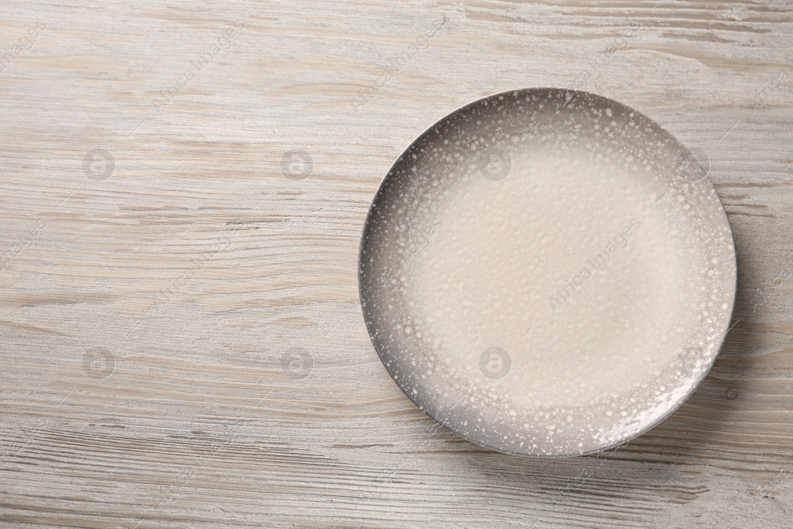 Photo of One ceramic plate on light wooden table, top view. Space for text