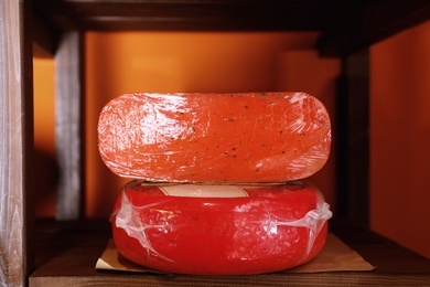 Photo of Delicious cheese on rack shelf in store. Dairy product