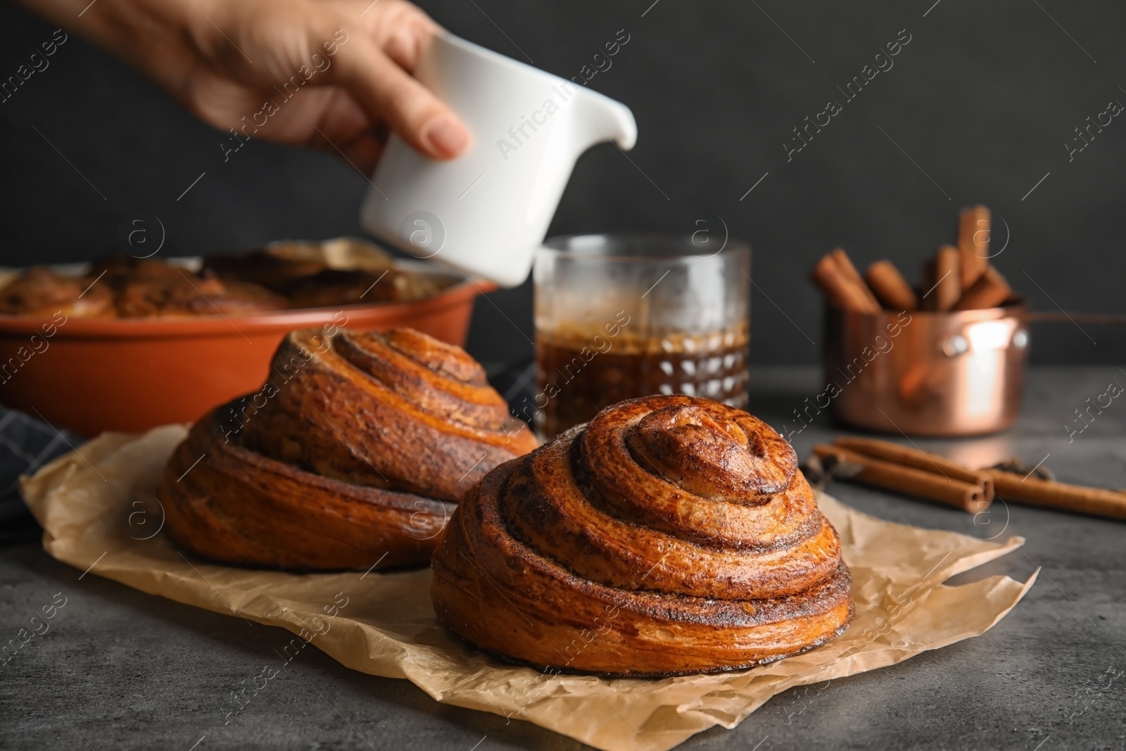 Photo of Parchment with freshly baked cinnamon rolls on table