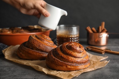 Photo of Parchment with freshly baked cinnamon rolls on table