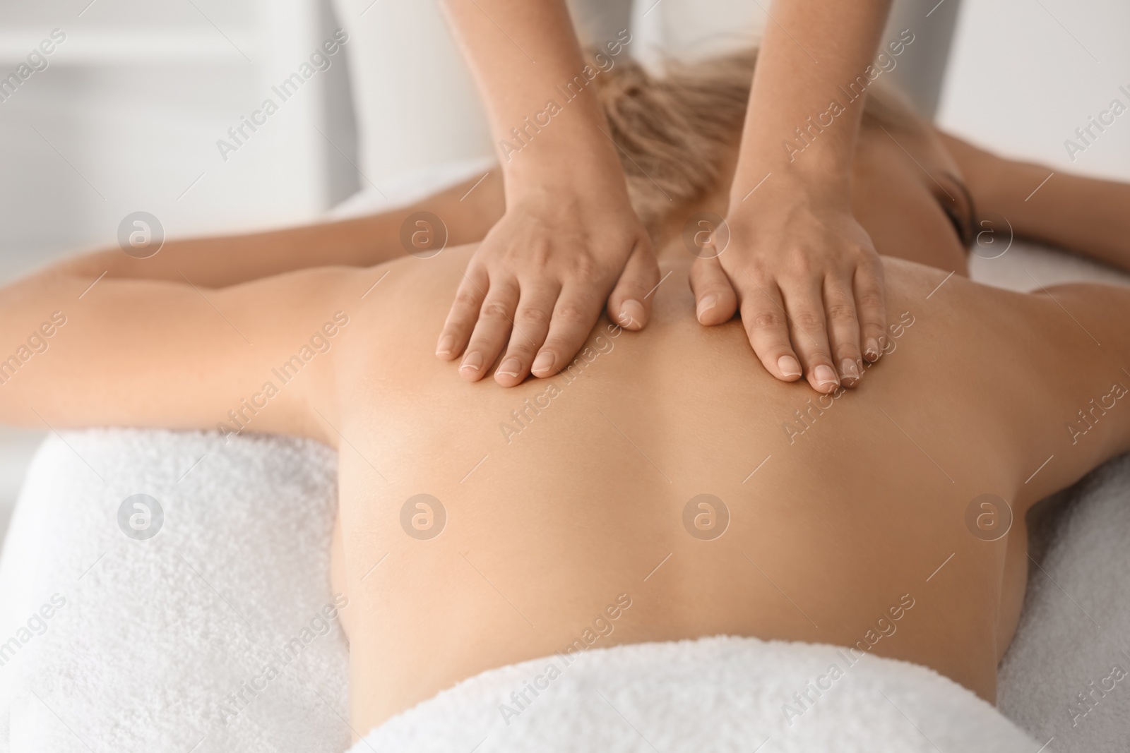 Photo of Relaxed woman receiving back massage in wellness center