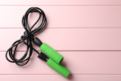 Photo of Skipping rope on pink wooden table, top view. Space for text