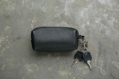 Photo of Leather case with keys on grey textured table, top view