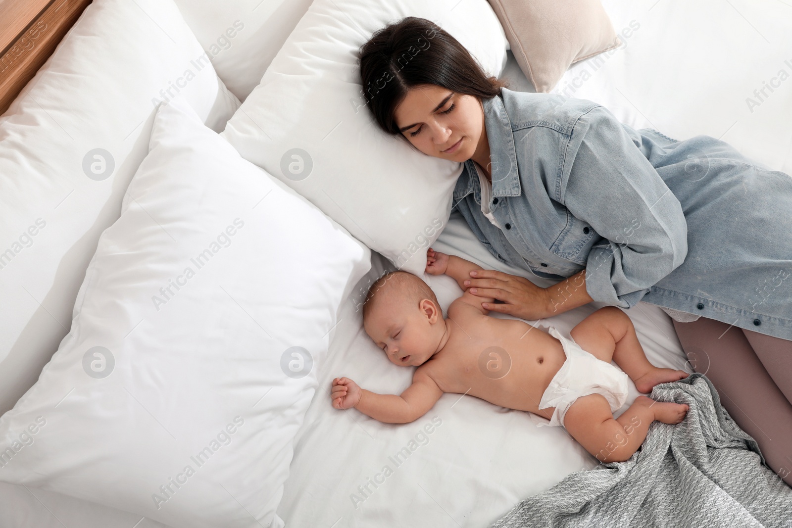 Photo of Mother with her cute baby sleeping on bed, above view