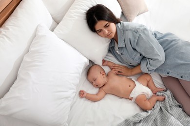 Mother with her cute baby sleeping on bed, above view