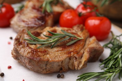 Photo of Delicious fried meat with rosemary, tomatoes and spices on white table, closeup