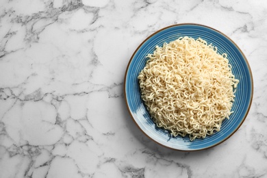 Plate of tasty noodles on marble background, top view. Space for text