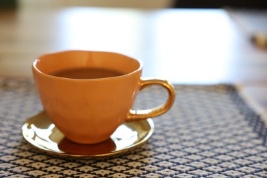 Photo of Cup of hot drink on table indoors, closeup. Space for text