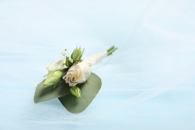 Photo of Wedding stuff. Stylish boutonniere and veil on light blue background, closeup. Space for text
