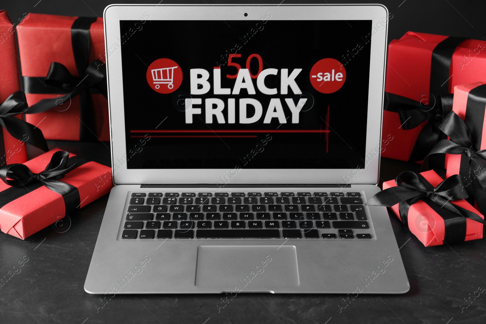 Photo of Laptop and gift boxes on table. Black Friday sale