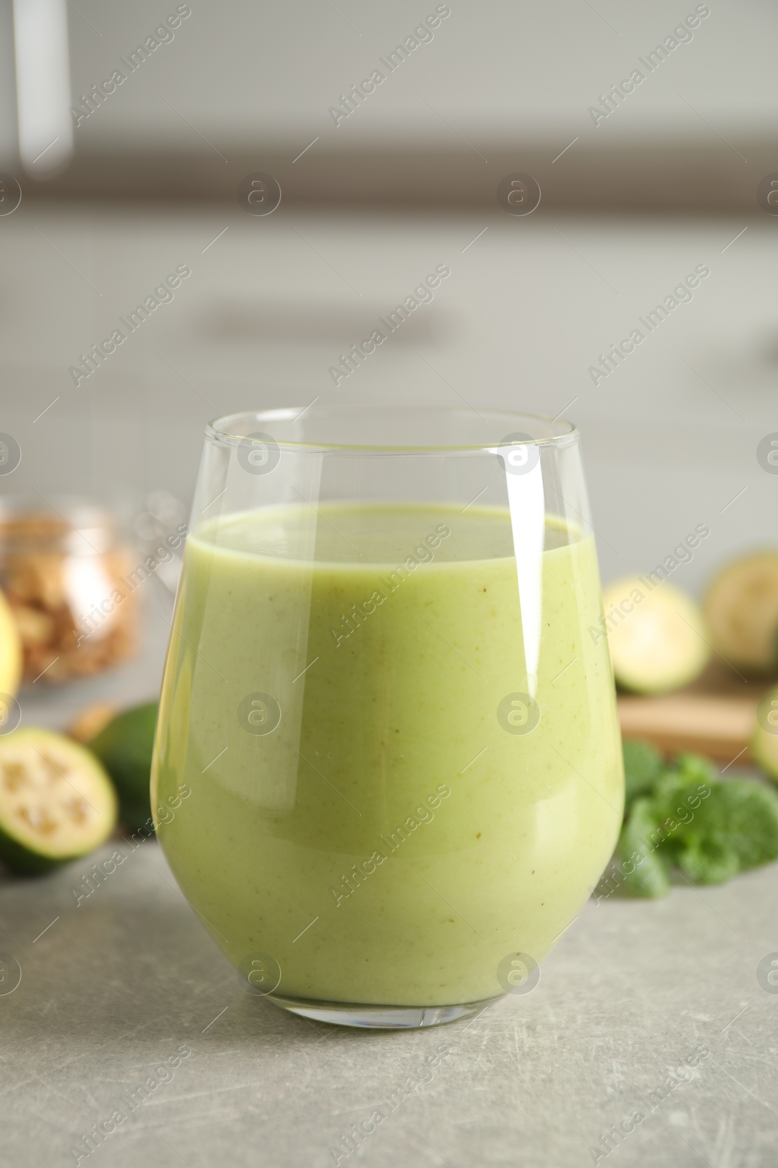 Photo of Fresh feijoa smoothie in glass on light grey table, closeup