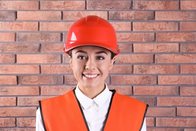 Female industrial engineer in uniform on brick wall background. Safety equipment