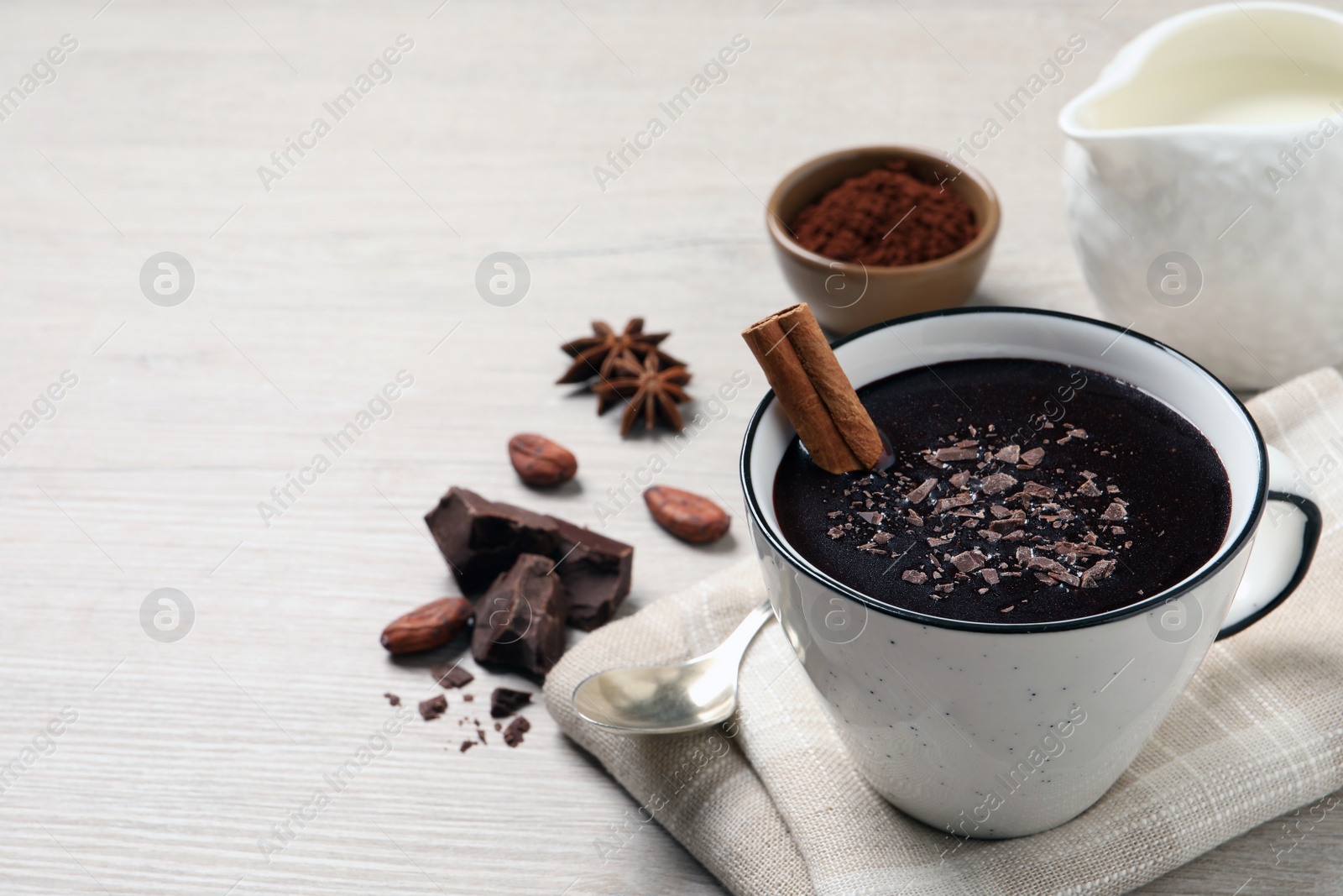 Photo of Yummy hot chocolate with cinnamon in cup on white wooden table. Space for text