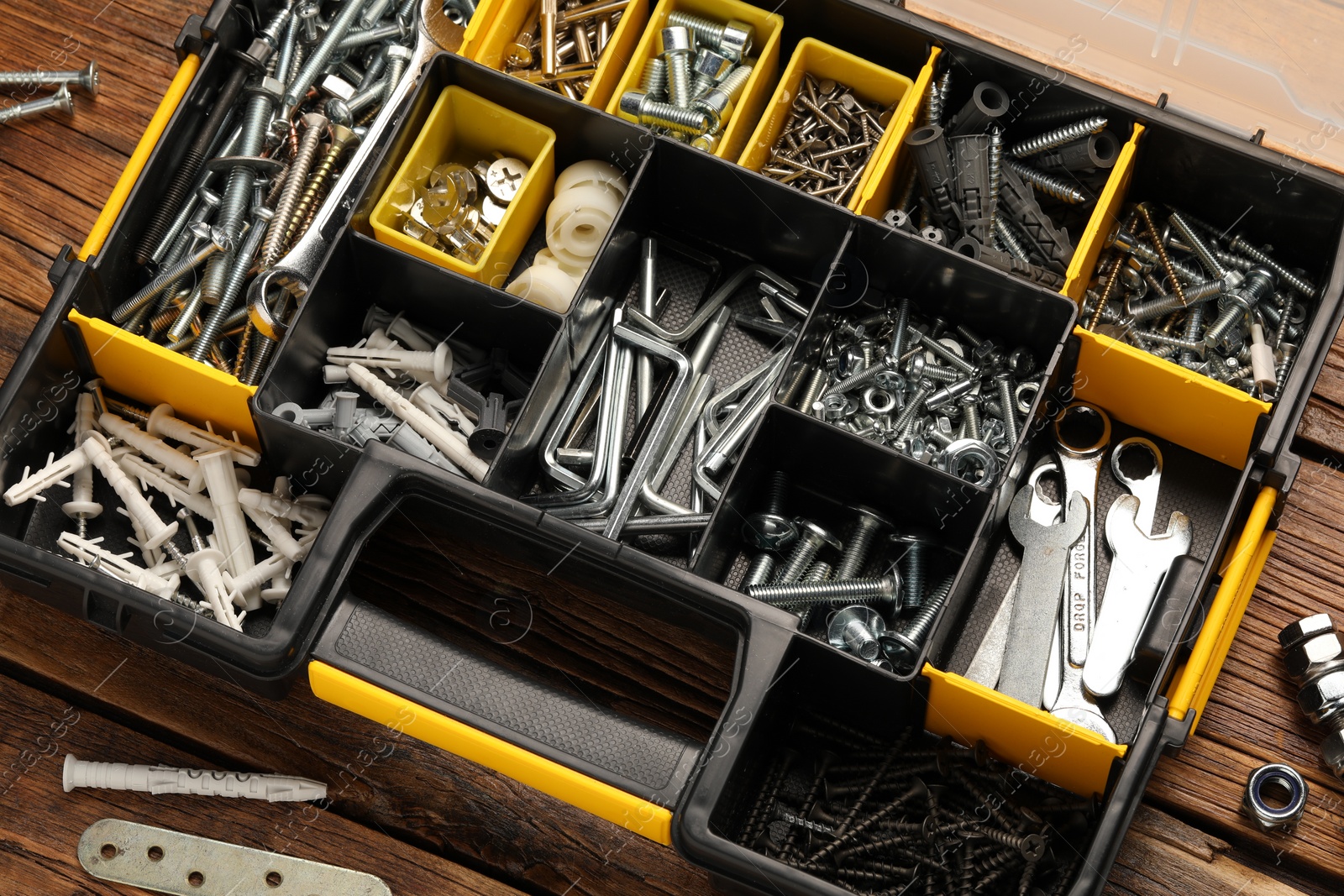 Photo of Organizer with many different fasteners and wrenches on wooden table, above view