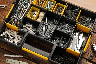 Organizer with many different fasteners and wrenches on wooden table, above view