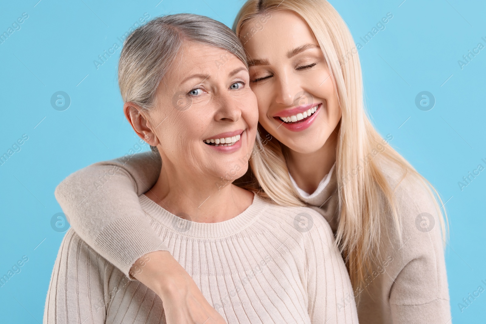 Photo of Family portrait of young woman and her mother on light blue background