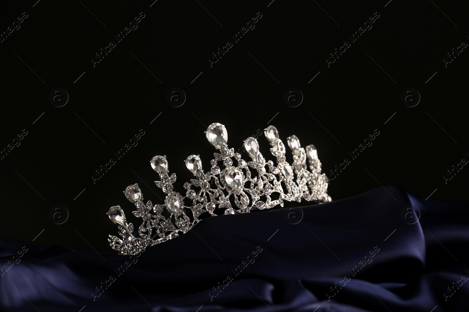 Photo of Beautiful silver tiara with diamonds on dark cloth. Space for text