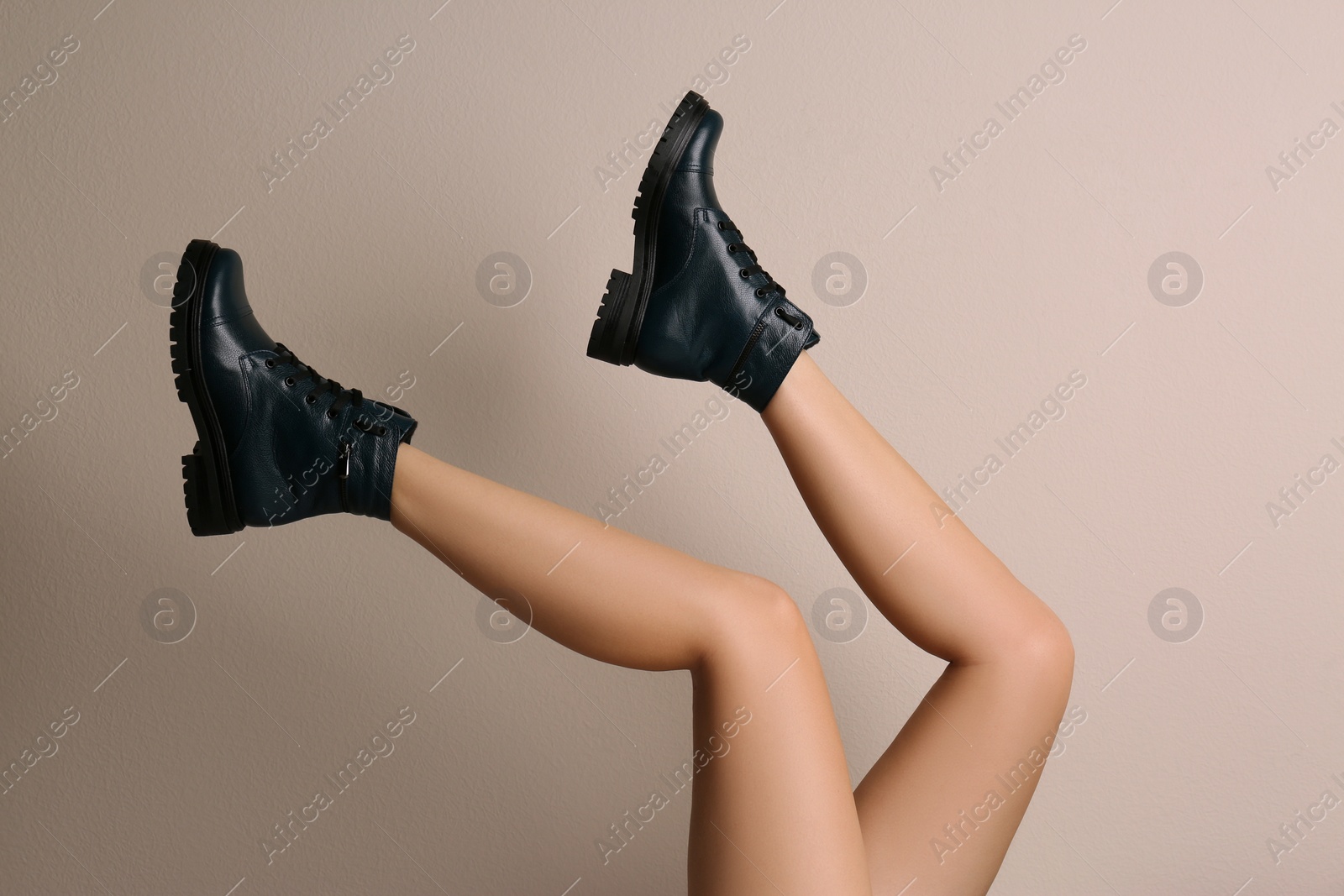 Photo of Woman wearing stylish boots on beige background, closeup