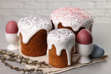 Photo of Tasty Easter cakes, decorated eggs and willow branches on grey table