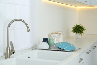 Photo of Clean dishes drying on rack in modern kitchen