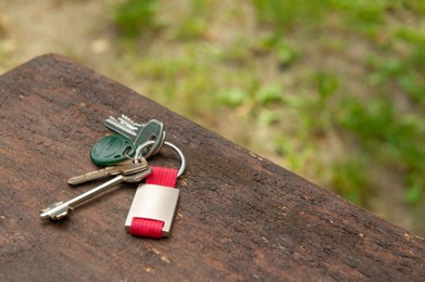 Photo of Keys forgotten on wooden bench outdoors, space for text. Lost and found