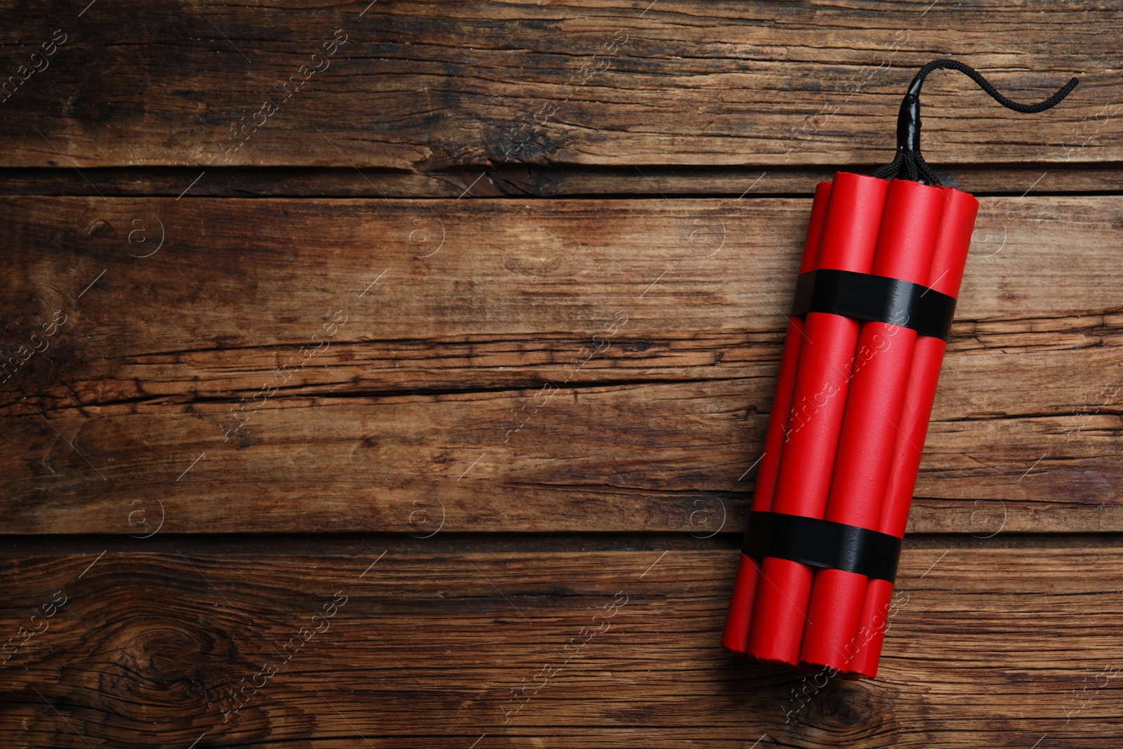 Photo of Red explosive dynamite bomb on wooden background, top view. Space for text