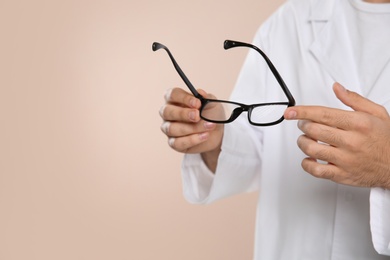Photo of Male ophthalmologist with eyeglasses on light background, closeup. Space for text